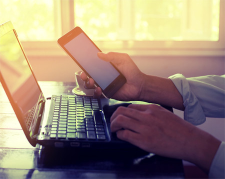 Side view shot of man hands working on his laptop and smart phone