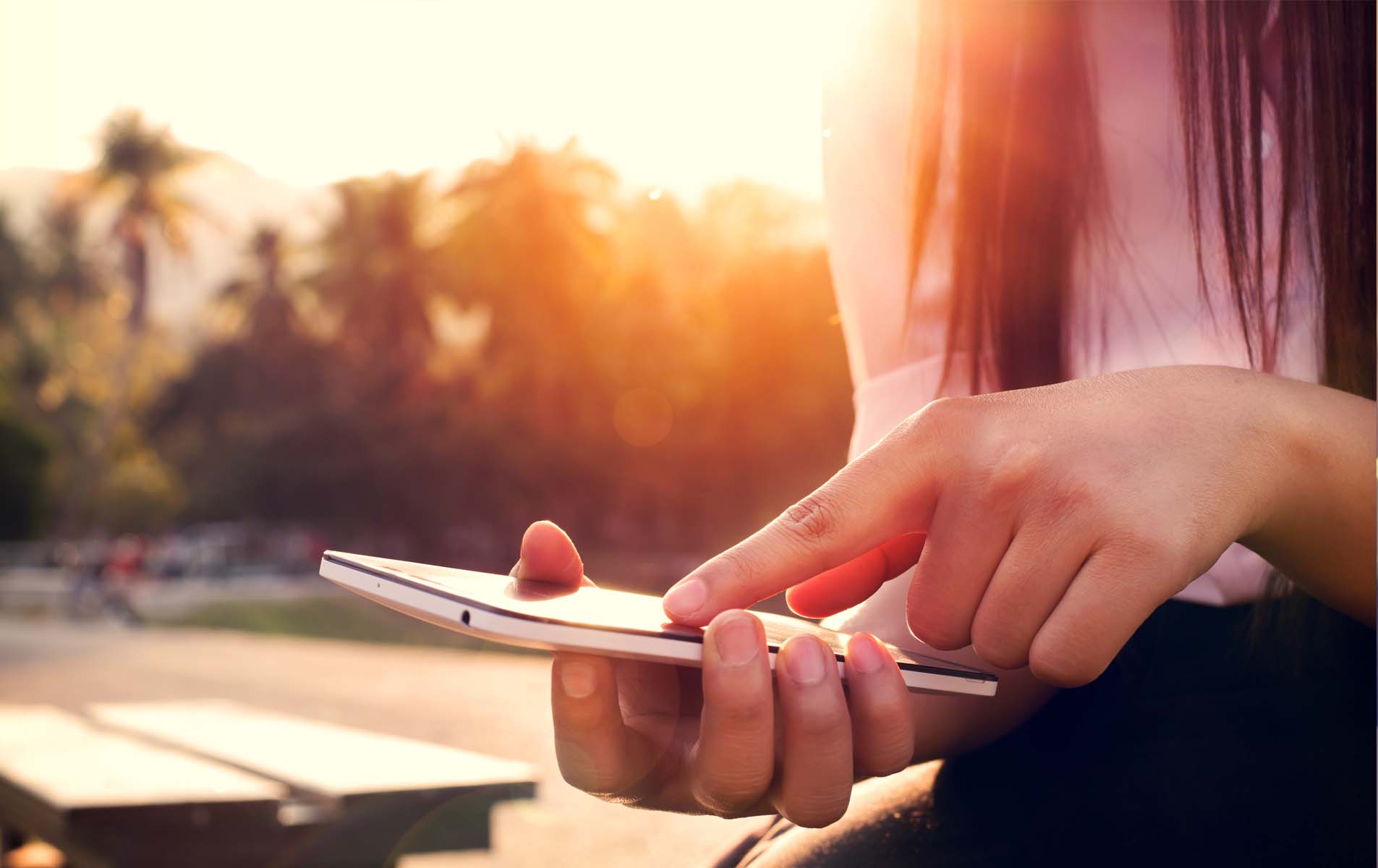 Close up of a woman using mobile smartphone in sunset Close up of a woman using mobile smartphone in sunset